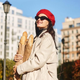 Shopper in red beret holding three baguettes and smiling